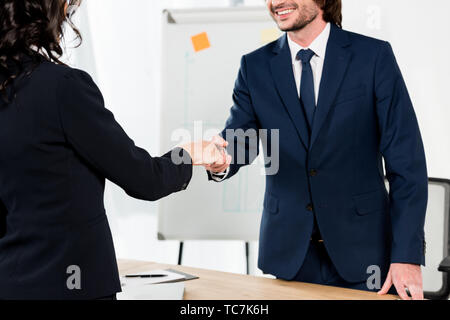 Vista ritagliata della felice reclutatore stringono le mani con brunette donna in ufficio Foto Stock
