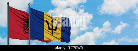 Albania e Barbados bandiera sventolare nel vento contro bianco torbido cielo blu insieme. Concetto di Diplomazia e relazioni internazionali. Foto Stock