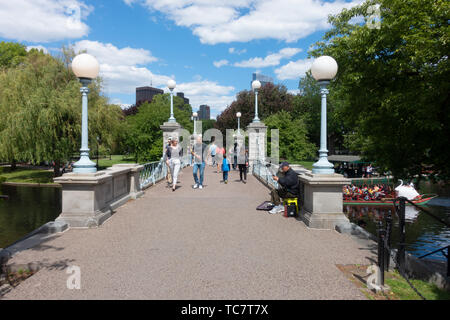 Passeggiate pedonali ponte sulla laguna con imbarcazione swan al Boston giardino pubblico adiacente al comune su una splendida giornata con le persone che attraversano le Foto Stock