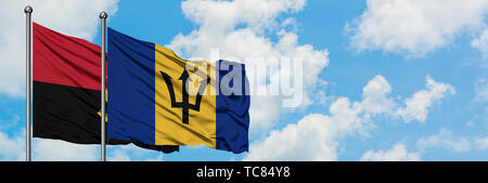 Angola e Barbados bandiera sventolare nel vento contro bianco torbido cielo blu insieme. Concetto di Diplomazia e relazioni internazionali. Foto Stock