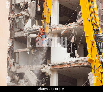 Demolizione di un edificio di nuova costruzione, utilizzando un escavatore speciale-cacciatorpediniere. Completare altamente meccanizzata di demolizione di strutture edili. Foto Stock