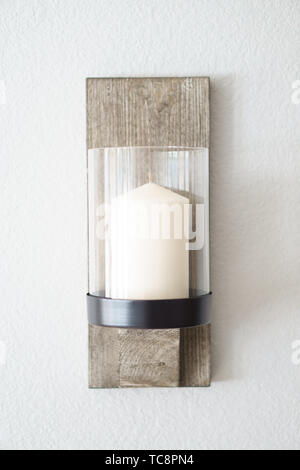 Lampada fatta a lume di candela con infisso in legno nel centro del muro bianco Foto Stock