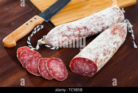 Tradizionale catalana Dry cured insaccato di maiale Longaniza con fette di pezzi sulla tavola di legno Foto Stock