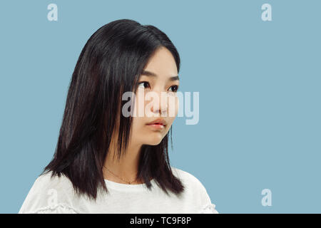 Il coreano giovane donna di mezza lunghezza verticale sul blu di sfondo per studio. Modello femminile in camicia bianca. Mantenere la calma e di attesa, guardando in avanti. Concetto di emozioni umane, l'espressione del viso. Vista frontale. Foto Stock