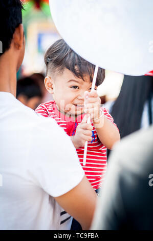 Un piccolo ragazzo cambogiano gioca felicemente con la sua mongolfiera in una giornata di famiglia a Phnom Penh, Cambogia. Foto Stock