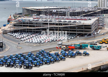 I trattori New Holland sulla banchina del Porto a Southampton Docks e Jaguar e Land Rover e Mini veicoli in attesa di esportazione. Picture Data: venerdì 31 maggio, 2019. Foto Stock