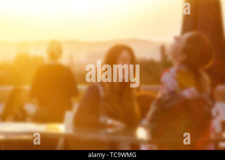 Defocalizzata persone che frequentano open air summer party sul tetto. Caldo sole di luce nella sera. Foto Stock