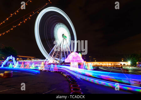 Blur ruotare lo spostamento della ruota panoramica Ferris con illuminazione al parco di carnevale in tempo di notte Foto Stock