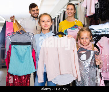 Ritratto di due felice allegro sorriso positivo bambine e i loro genitori con nuovi vestiti nel centro commerciale per lo shopping Foto Stock