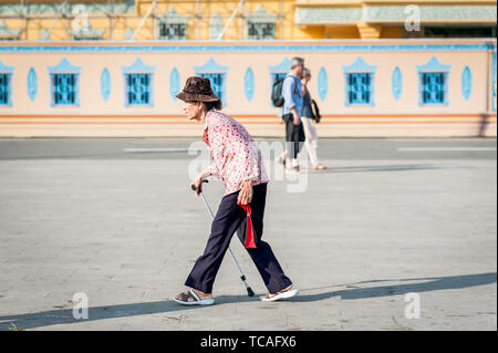 Una vecchia signora cambogiana fa il suo modo attraverso la strada di fronte al Grand Palace, Phnom Penh Cambogia del Sud Est Asiatico. Foto Stock