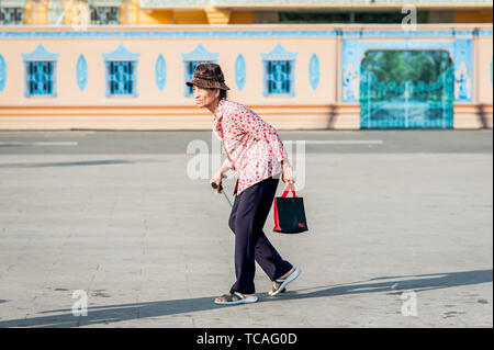 Una vecchia signora cambogiana fa il suo modo attraverso la strada di fronte al Grand Palace, Phnom Penh Cambogia del Sud Est Asiatico. Foto Stock