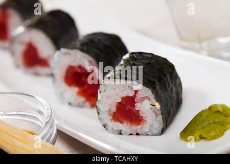 Tonno fresco maki sushi servita su piastra bianca con wasabi e salsa di soia Foto Stock