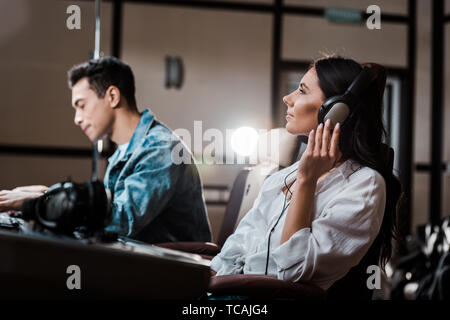 Bello produttore del suono lavora alla console di miscelazione mentre il suo collega ascoltando la musica nelle cuffie Foto Stock