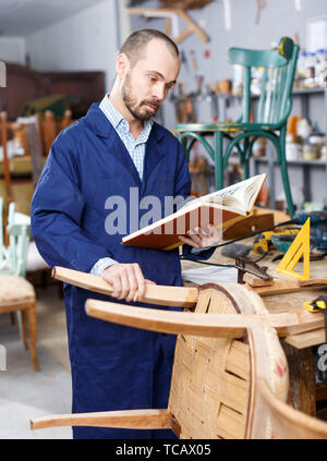 Professional Restauratore riparatore azienda album nelle sue mani in legno studio Foto Stock