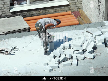 06 05 2019 Russia, Brjansk. Un uomo che lavora con una taglierina taglia un mattone in mezzo. Foto Stock