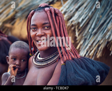 Ritratto di una giovane donna himba con suo figlio indossando il tradizionale acconciatura Foto Stock