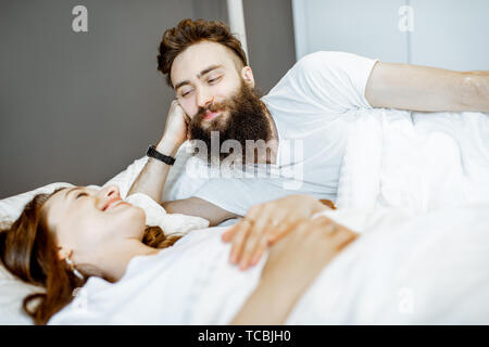 Giovane coppia adorabile giacente insieme nel letto di conversazione romantica prima del sonno Foto Stock