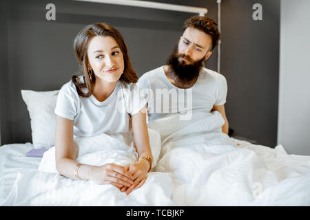 Coppia giovane avendo problemi in relazione intima, sensazione triste mentre è seduto nel letto di casa Foto Stock