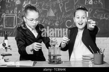 Prestare attenzione a eseguire la reazione chimica. Conoscenze di base di chimica. Ragazze studio chimica. Fare studiare la chimica interessante. Esperimento educativo concetto. Microscopio e provette per la prova sul tavolo. Foto Stock