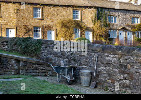 Il pittoresco villaggio di Downham, Lancashire, nel Ribble Valley, Regno Unito Europa mostra tradizionale cottage in pietra . Giardinieri carriola, benne un Foto Stock