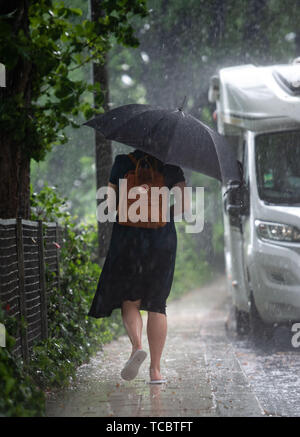 Berlino, Germania. Il 6 giugno, 2019. Una donna con un ombrello passeggiate attraverso la pioggia. Credito: Lisa Ducret/dpa/Alamy Live News Foto Stock