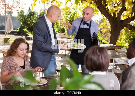 Conflitto tra il cameriere e client nel ristorante all'aria aperta Foto Stock