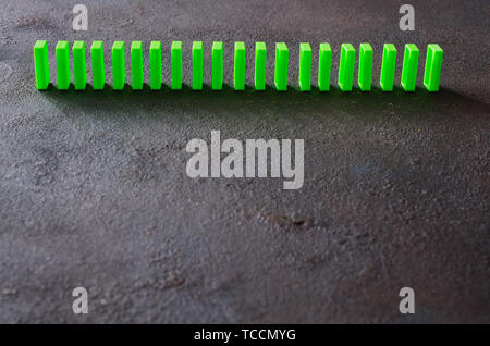 Effetto domino. Fila di domino di verde su sfondo scuro. Copia dello spazio. Foto Stock