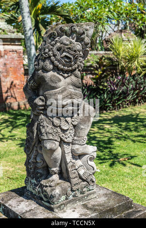 Klungkung, Bali, Indonesia - 26 Febbraio 2019: Closeup di pietra grigia statua di uomo con testa leone immerso nel verde giardino. Foto Stock