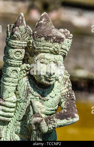 Klungkung, Bali, Indonesia - 26 Febbraio 2019: primo piano della statua di pietra della persona con club, totalmente coperta di verde e nero stampo. Foto Stock