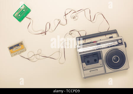 Vecchia radio con registratore a nastri e cassette con nastro formando un filo. Piatto stile di laici. Foto Stock