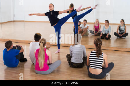 Giovane femmina istruttore di danza dimostra la nuova posizione di studenti adolescenti Foto Stock