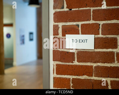 Per uscire da firmare su un muro di mattoni in un magazzino moderno lobby e area ufficio Foto Stock