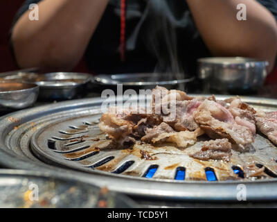 Manzo cotto petto le fette su grill al barbeque Coreano fumare nel ristorante con uomo Foto Stock