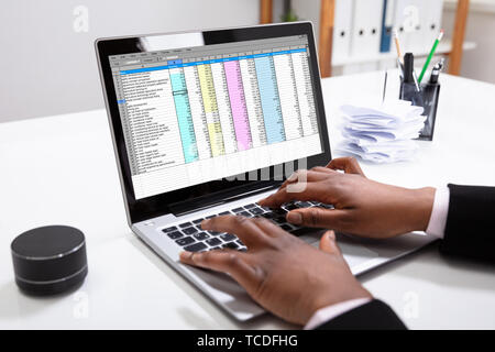 Close-up di una imprenditrice la mano esaminando i rapporti sul computer portatile in ufficio Foto Stock