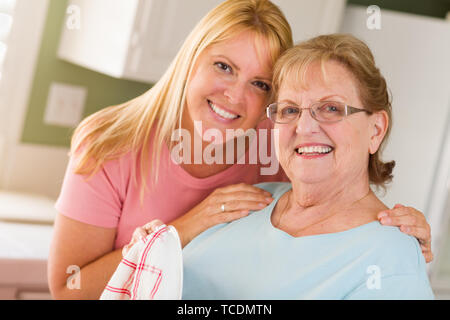 Ritratto di sorridere Senior donna adulta e giovane figlia al lavello in cucina. Foto Stock