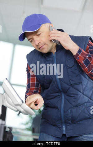 Uomo al telefono che fissa un ufficio stampante Foto Stock