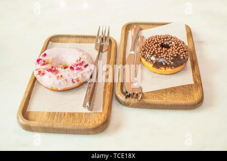 Delicicous ciambelle dolci su piastre di legno su un tavolo in un bar. Foto Stock