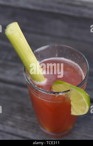 Una bevanda Clamato con sedano, sale e linea in una pinta bicchiere seduto su un vecchio ponte di legno. Foto Stock