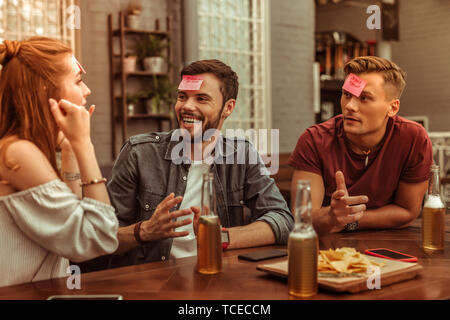 Allegro amici. Felice allegro sostenuto sorridente la trasmissione via IR di gioiosa bella vigorosa giovani-adulti tre amici condividendo una risata al bar e playi Foto Stock