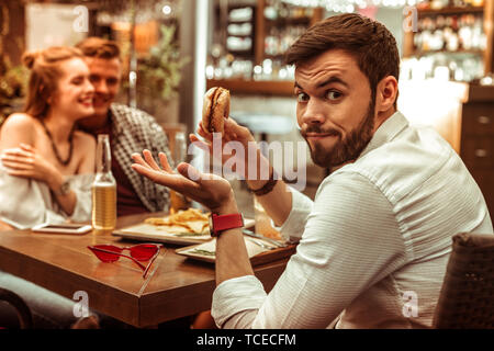 Scrollare le spalle. Volto ritratto di bella bella stupiti scioccato dispiacque a pelo corto maschio barbuto uncomprehendingly scrollare le spalle Foto Stock