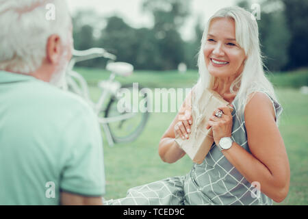 Per voi. Felice donna felice tenendo un regalo mentre che vogliono dare a suo marito Foto Stock