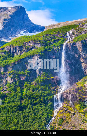 Cascata, mountain cliff e alberi verdi sul modo di Briksdal o ghiacciaio Briksdalsbreen in Olden, Norvegia Foto Stock