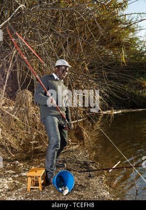 Emotional ritratto di uomo africano tirando con asta di pescare sul fiume Foto Stock