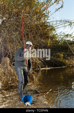 Emotional ritratto di uomo africano tirando con asta di pescare sul fiume Foto Stock