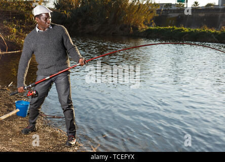 Emotional ritratto di uomo africano tirando con asta di pescare sul fiume Foto Stock