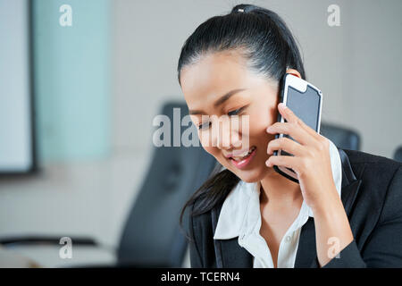 Bella giovane vietnamita business lady parlando al telefono quando lavoro in ufficio Foto Stock