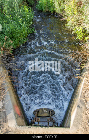 Da sopra il colpo di fretta acqua dalla berlina in calcestruzzo canale di drenaggio e fluente in creek tra erba verde Foto Stock