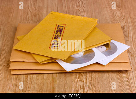 Le buste con il lato superiore top secret timbro con dischi CD su sfondo di legno Foto Stock