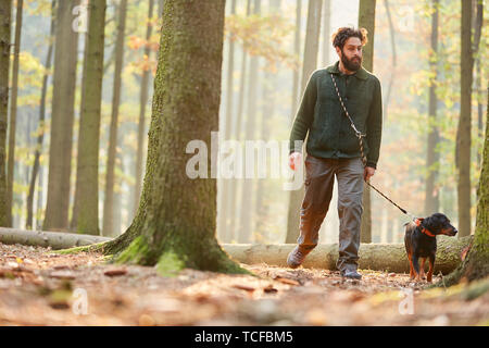 Cacciatori o silvicoltori andare a fare una passeggiata in un bosco con un cane come un cane da caccia Foto Stock