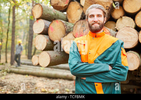 Foresta di giovane agricoltore di fronte a un lungo legno carrello è felice circa il raccolto Foto Stock